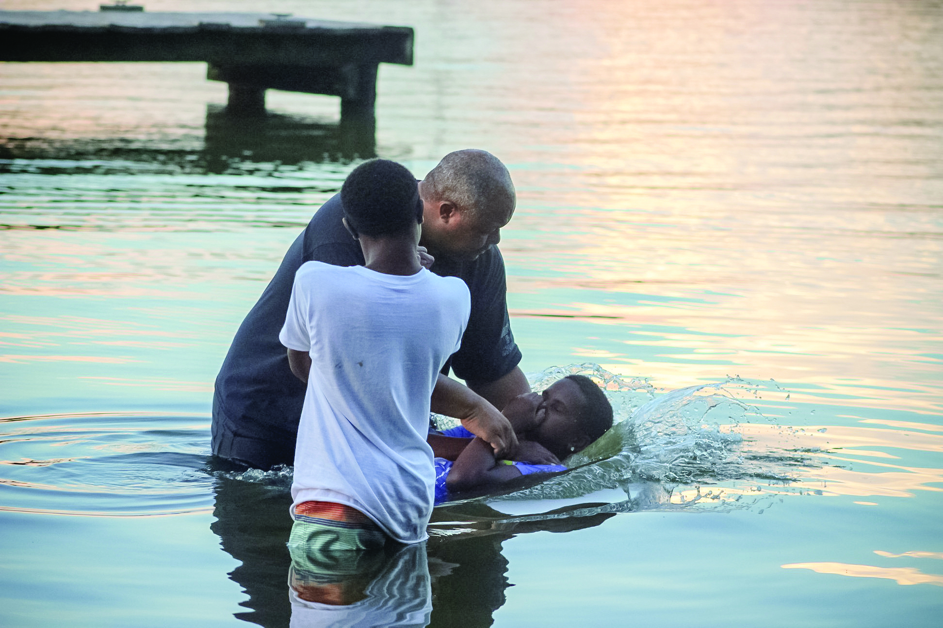 The Rev. Tim Warner baptizes two young boys at West River during Camp Hope.