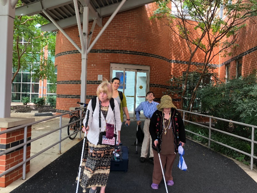 A group of individuals arriving to the conference- 2 persons using canes 1 person using crutches