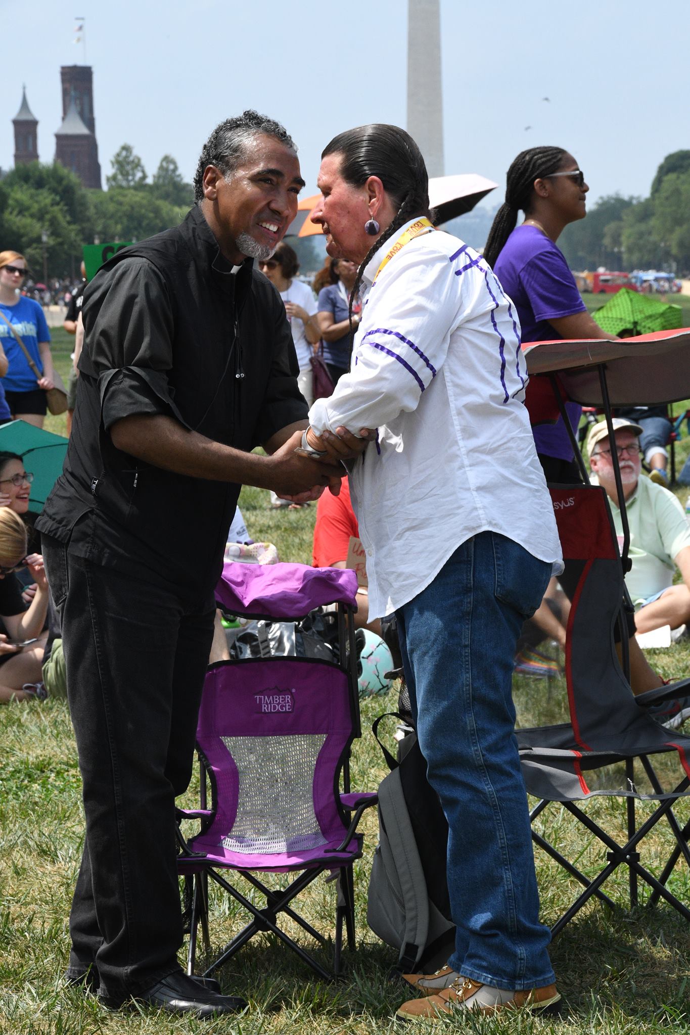 Two men shaking hands on the mall with the Washington monument in the background