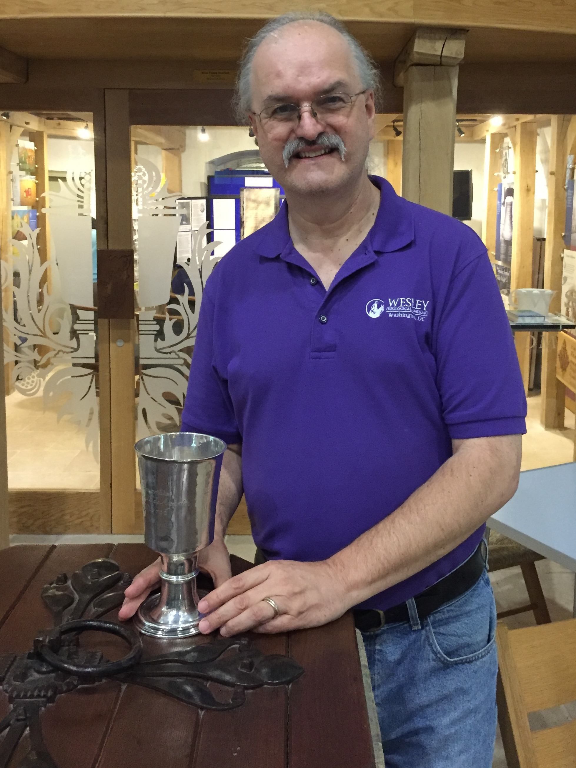 The author stands at the baptismal font used to baptize John and Charles Wesley at St. Andrew’s Church in Epworth. The silver chalice was also used by the Wesley  brothers.