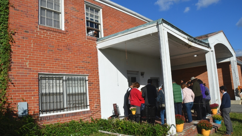 Church members and civic leaders pray on the front porch of the new UMC House at Van Buren UMC in Washington, D.C. Photo by Erik Alsgaard.